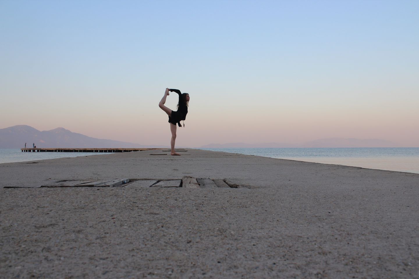 A person performing yoga at sunset on a dock in Kuşadası, Turkey.